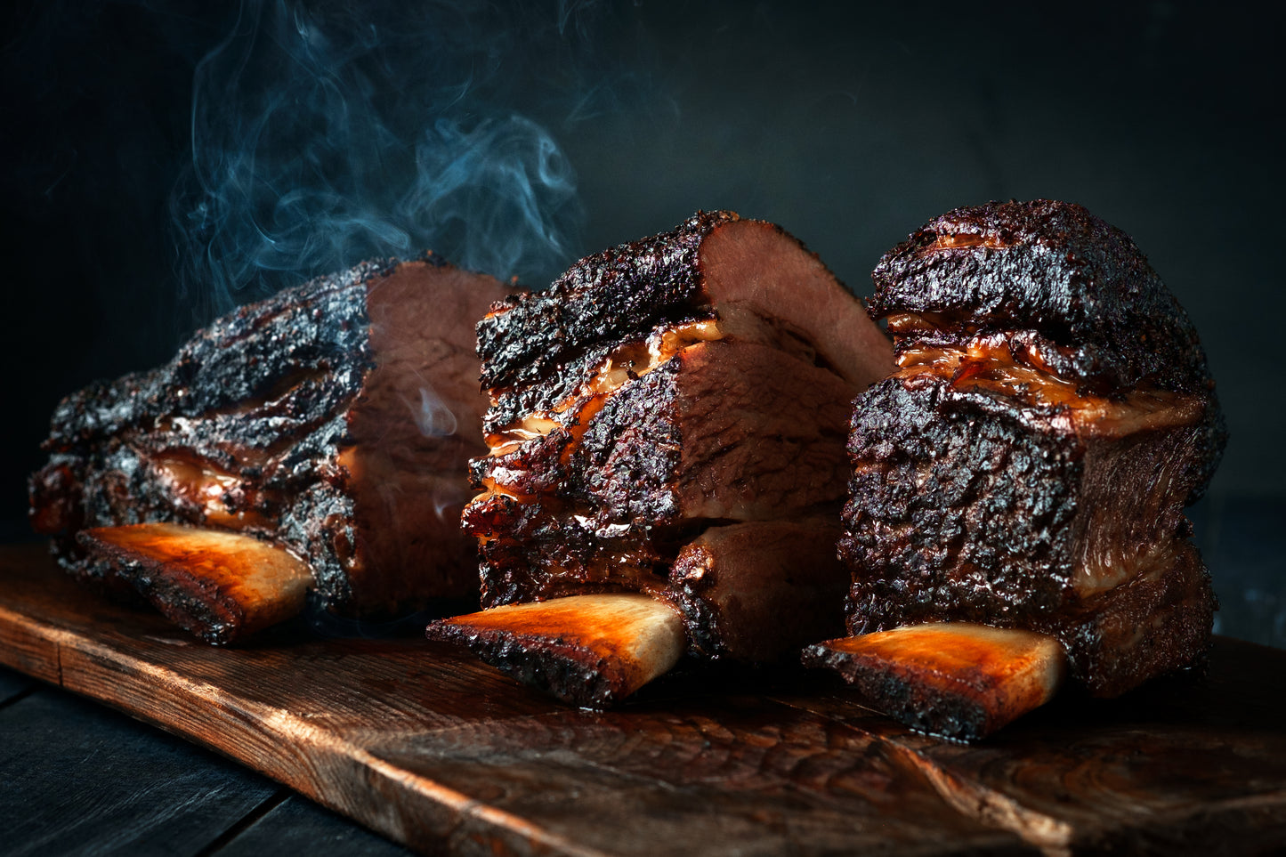 Steaming American Wagyu short ribs charred on wood cutting board