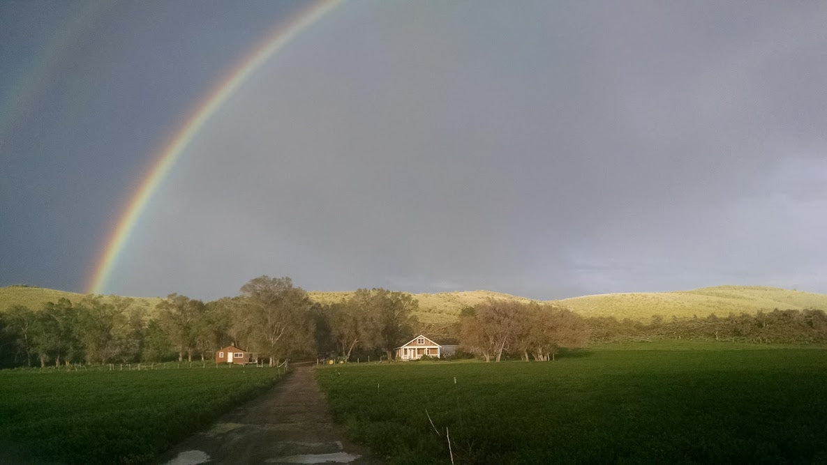 Rainbow over farm house bennion ranch May with greenjacket hills in background and alfalfa in foreground