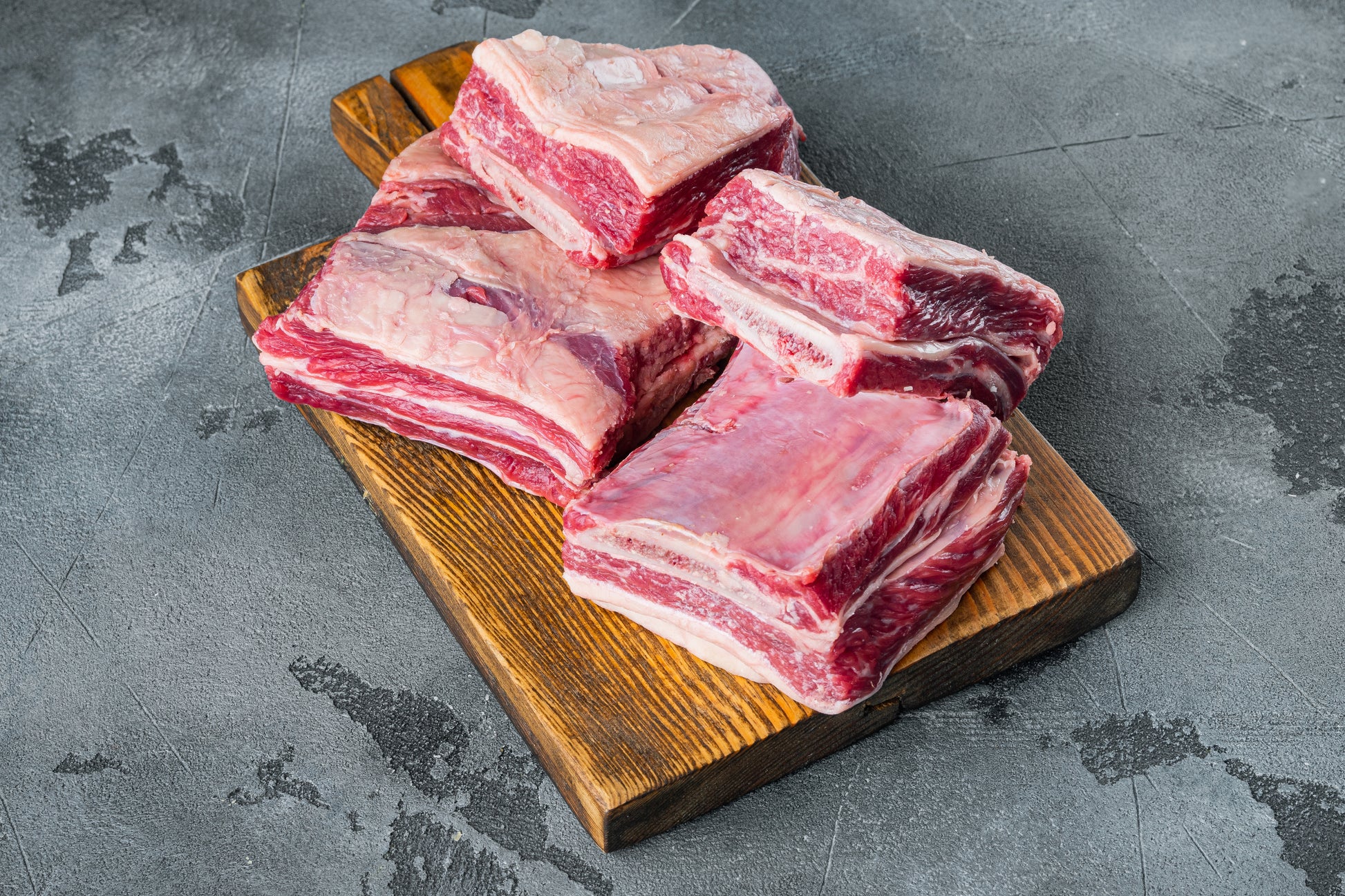 Raw Short Ribs American Wagyu on wooden chopping block